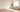 Sunlit living room with a cream sofa, area rug, hardwood floor, and ceiling fan