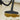 A close-up of a black floor vacuum cleaner head cleaning up a brown liquid spill on a beige tiled floor.
